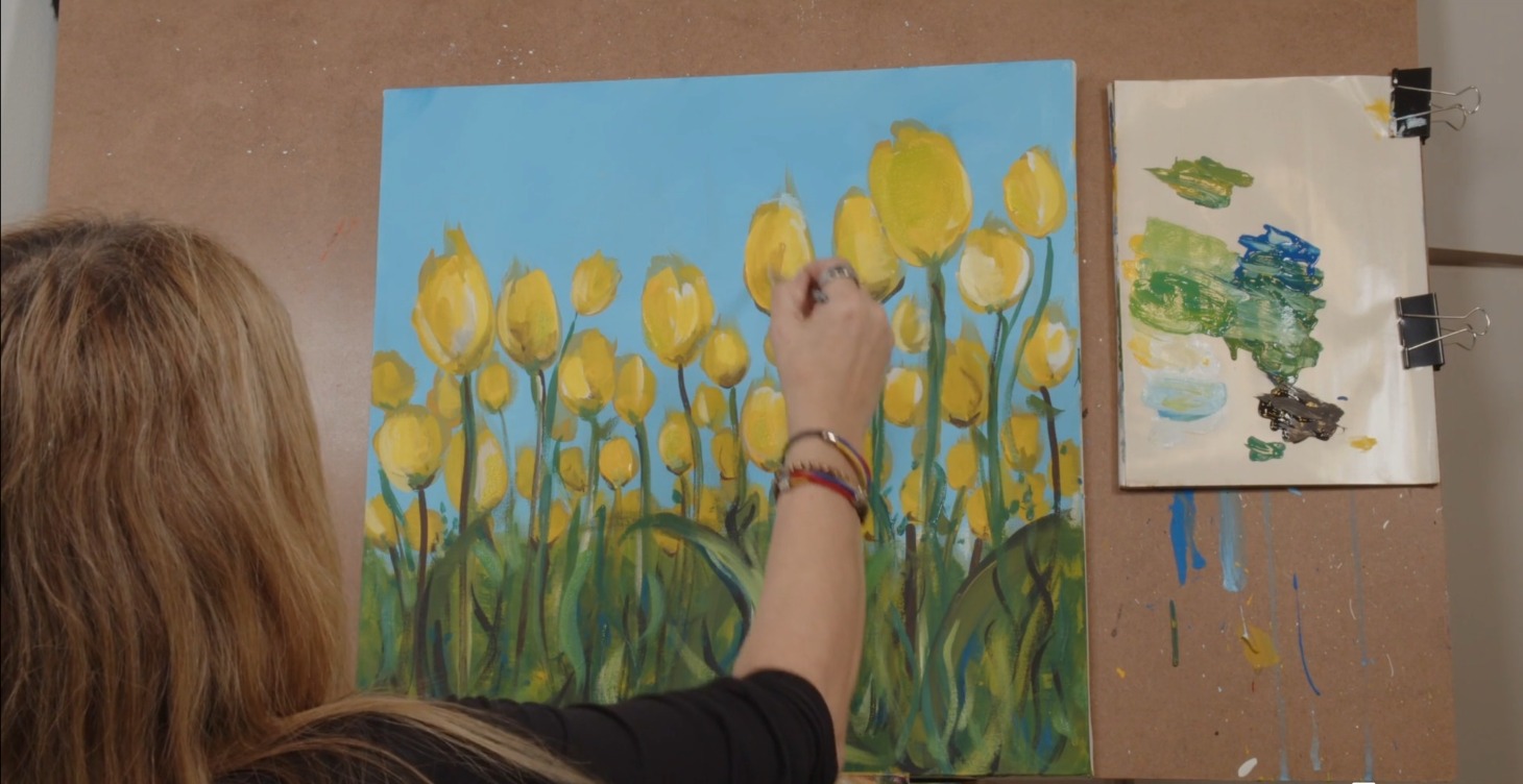 Hand painting a field of yellow tulips against a bright blue sky