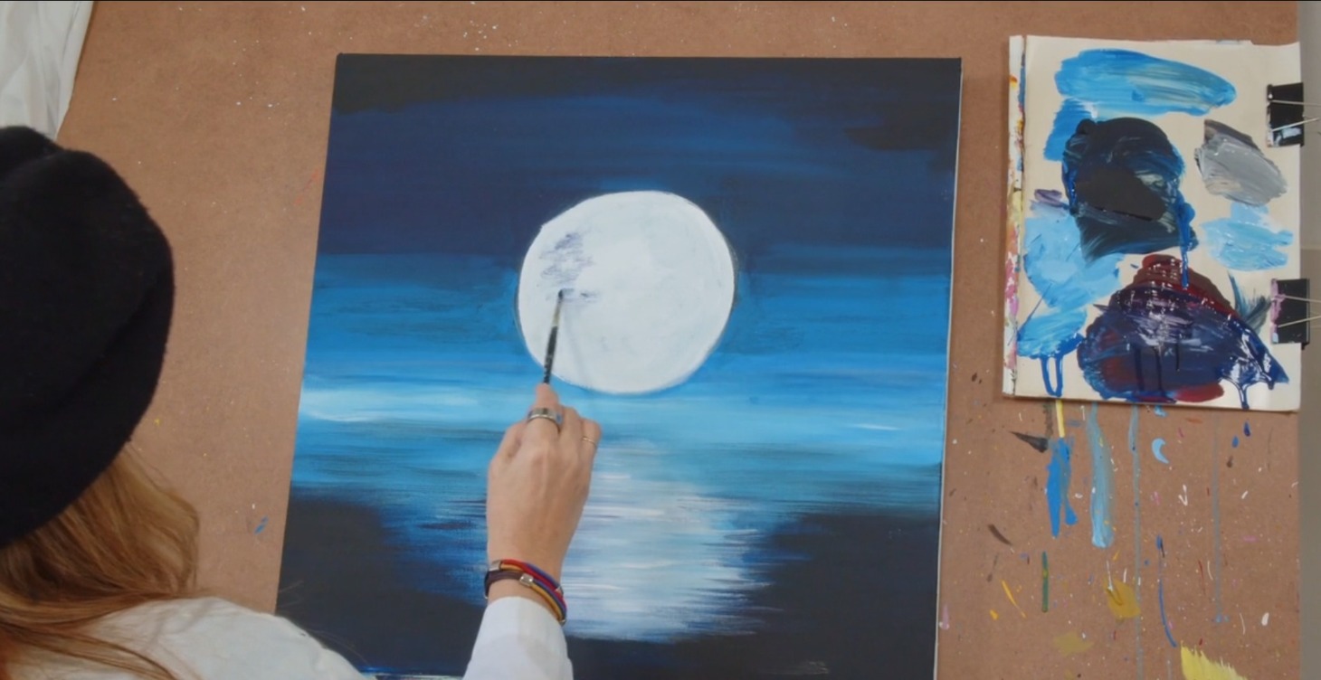 Hand painting a bright full moon reflecting on dark water