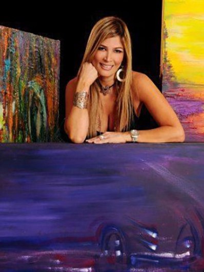 Michelle Betancourt smiling beside her colorful original paintings